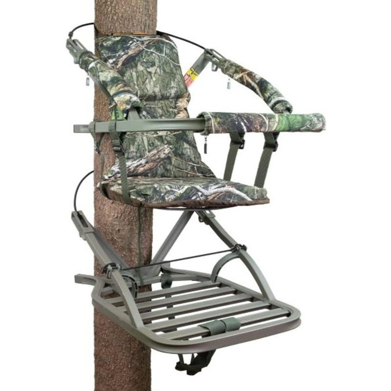 A hunting ground blind set up in a natural outdoor setting, camouflaged among trees and foliage. The blind is designed to blend in with the surroundings, providing a concealed area for hunters.